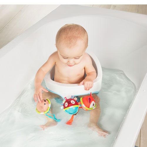 Een baby in een badzitje speelt in bad met de drie Lilliputiens badballen met dierenfiguren.