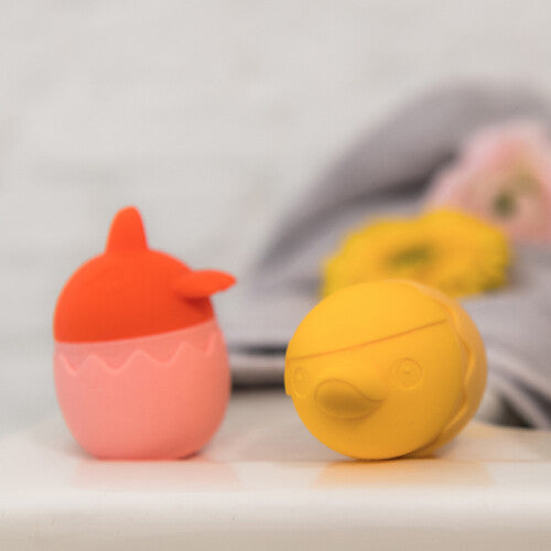 Twee Lilliputiens badspeeltjes staan naast elkaar, een oranje kuiken en een geel rond dier.