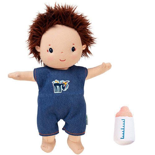 Lilliputiens lappenpop Charlie met bruin haar en blauwe romper staat naast een wit flesje.
