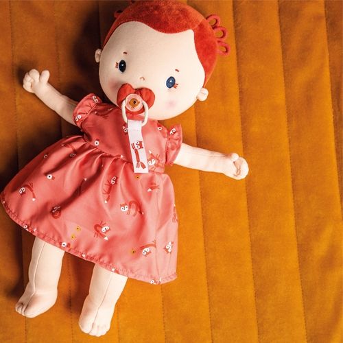Lilliputiens lappenpop Rose met rode jurk en speen, liggend op een gele deken.