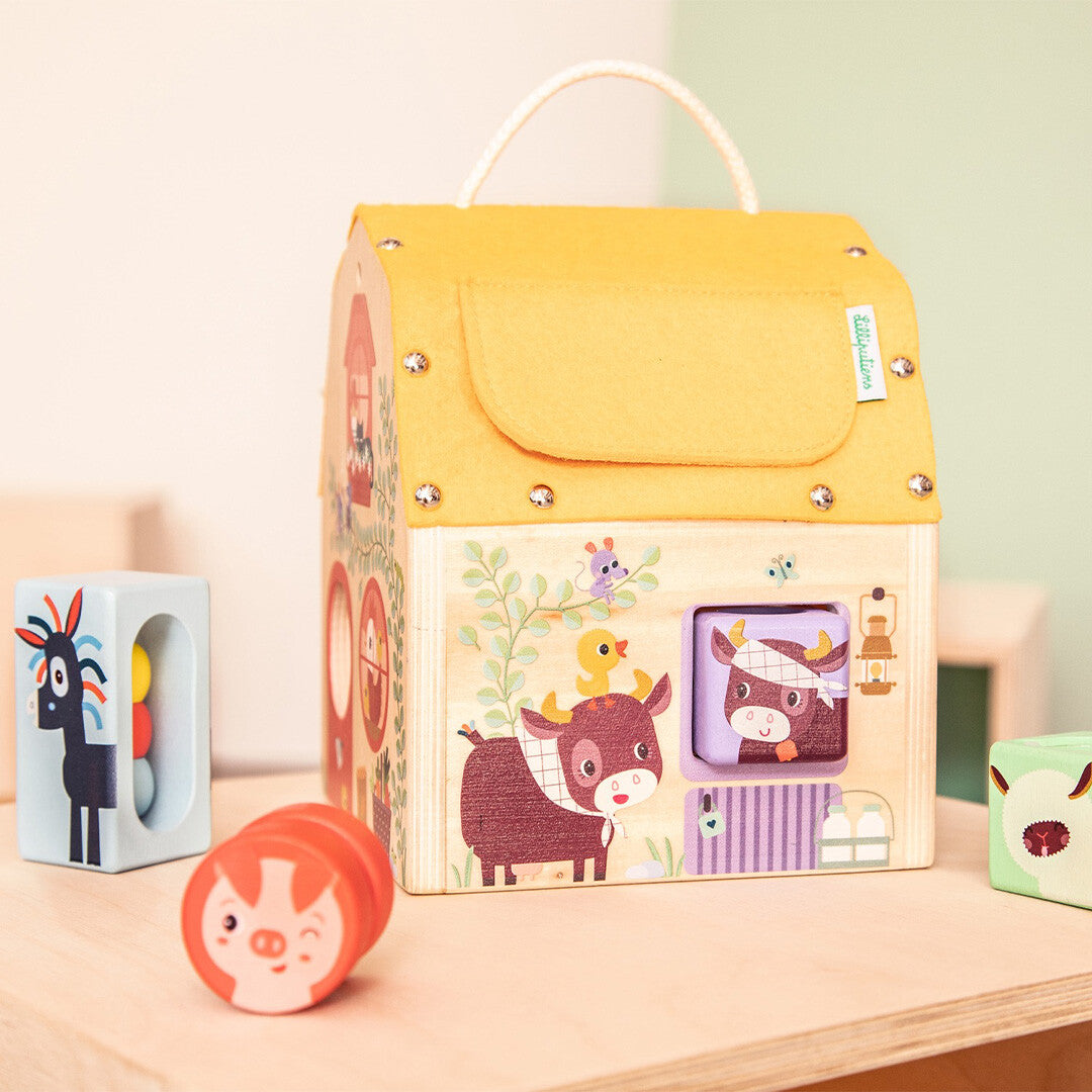 Zijkant van het Lilliputiens houten ontdekkingshuis met een koe-illustratie en twee dierenvormen ernaast.