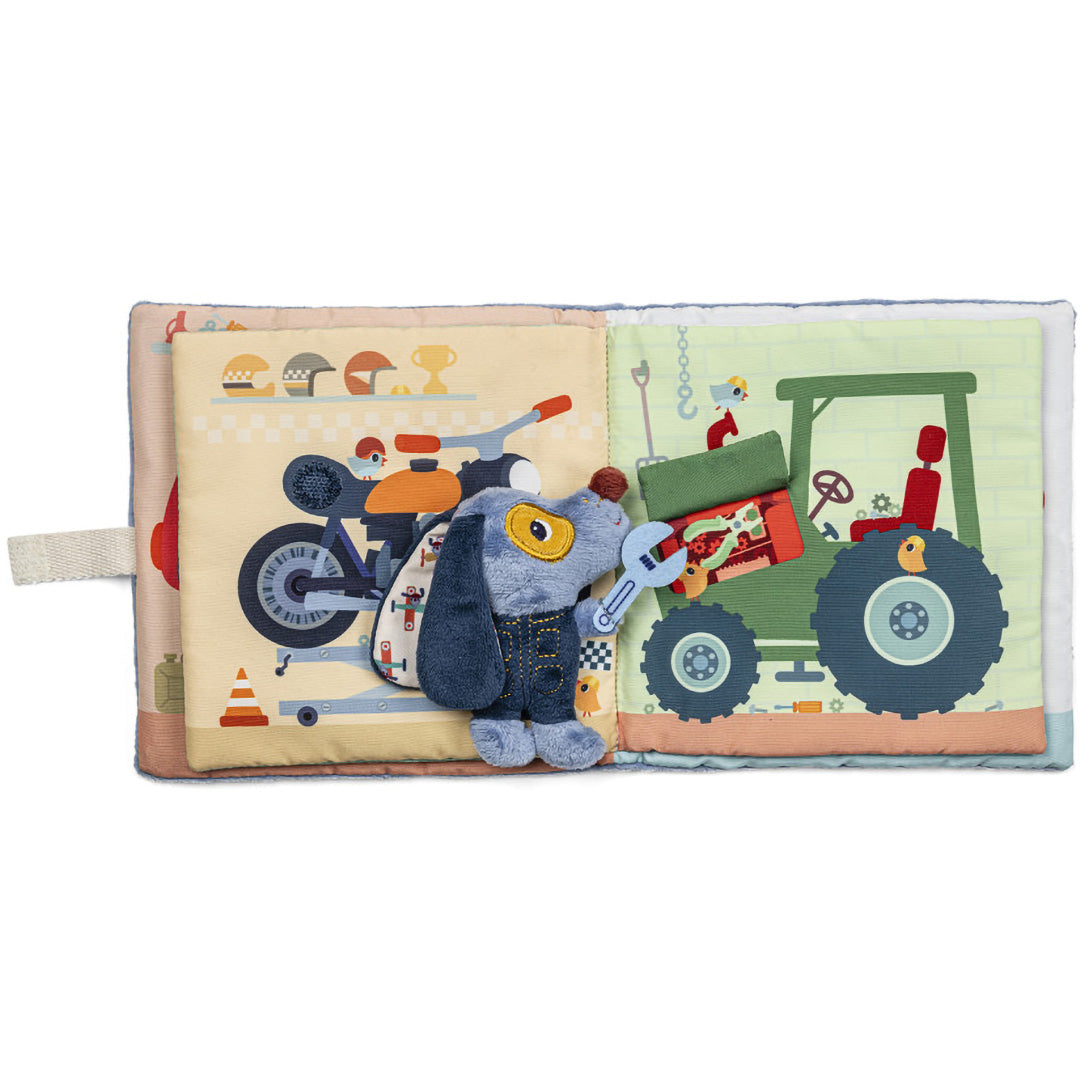 Lilliputiens stoffen activiteitsspeelboek open, met een motor en Jules de hond naast een groene tractor op de pagina's.