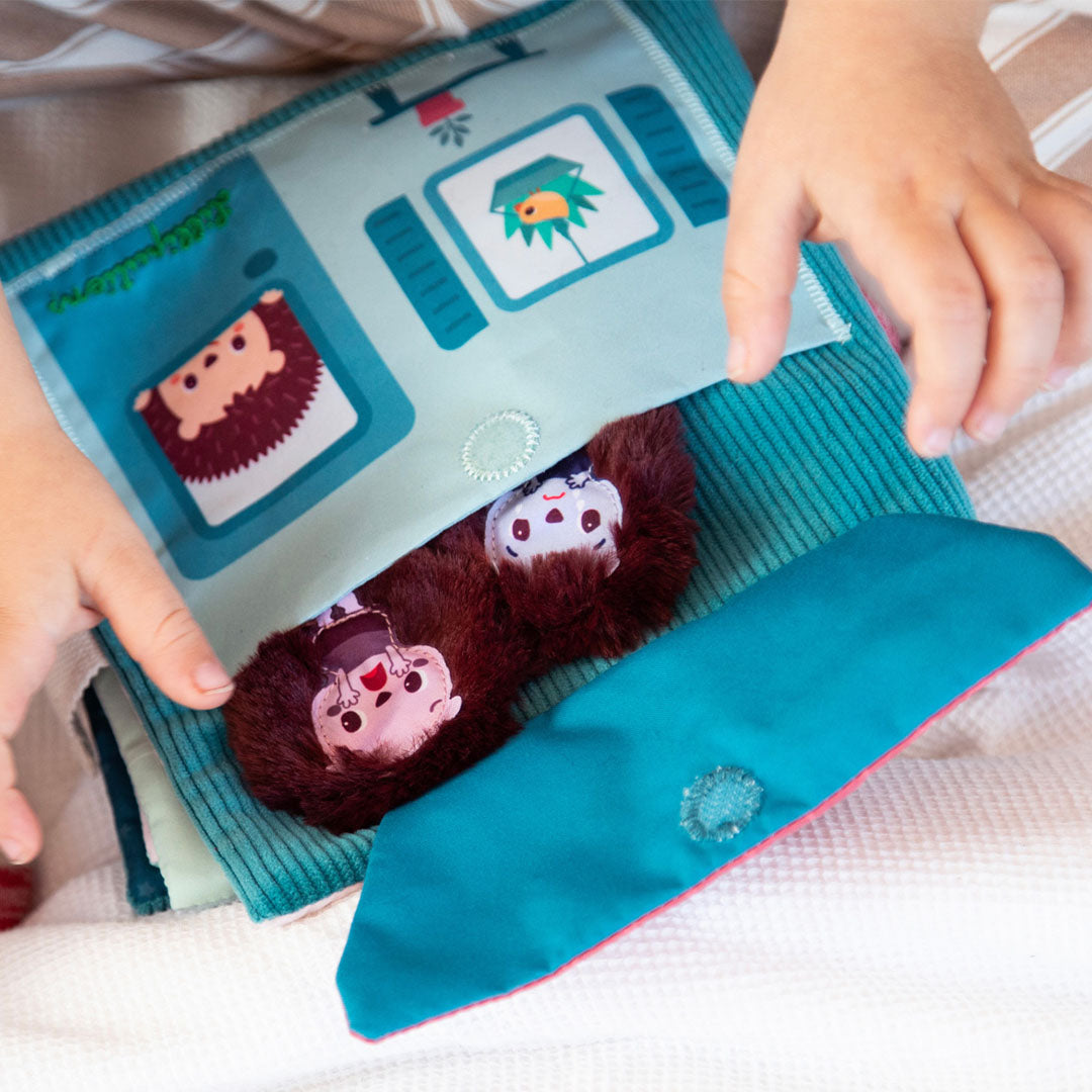 Kinderhanden openen een flap van het Lilliputiens activiteitenboek waar twee egelpoppetjes onder vandaan komen.