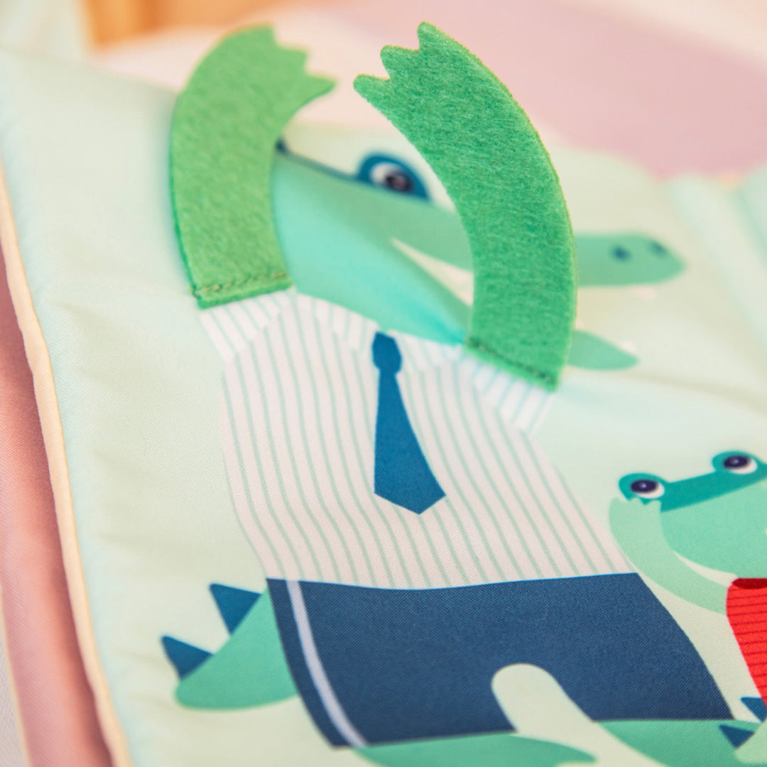 Detail van een pagina uit het activiteitenboek met een groene krokodil in een gestreept overhemd en blauwe stropdas.