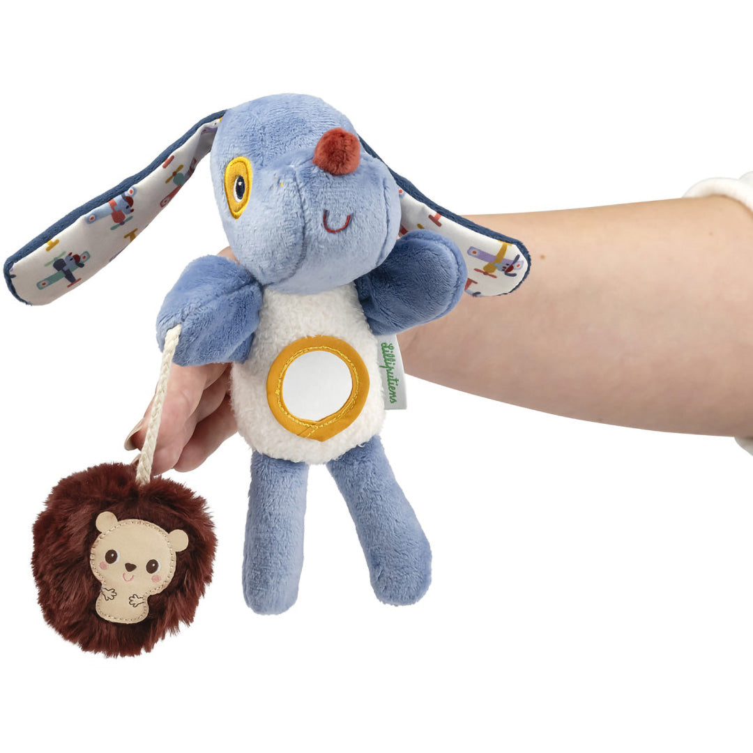Een hand houdt de Lilliputiens Jules activiteiten handpop met rammelaar vast, met de spiegel op de buik.