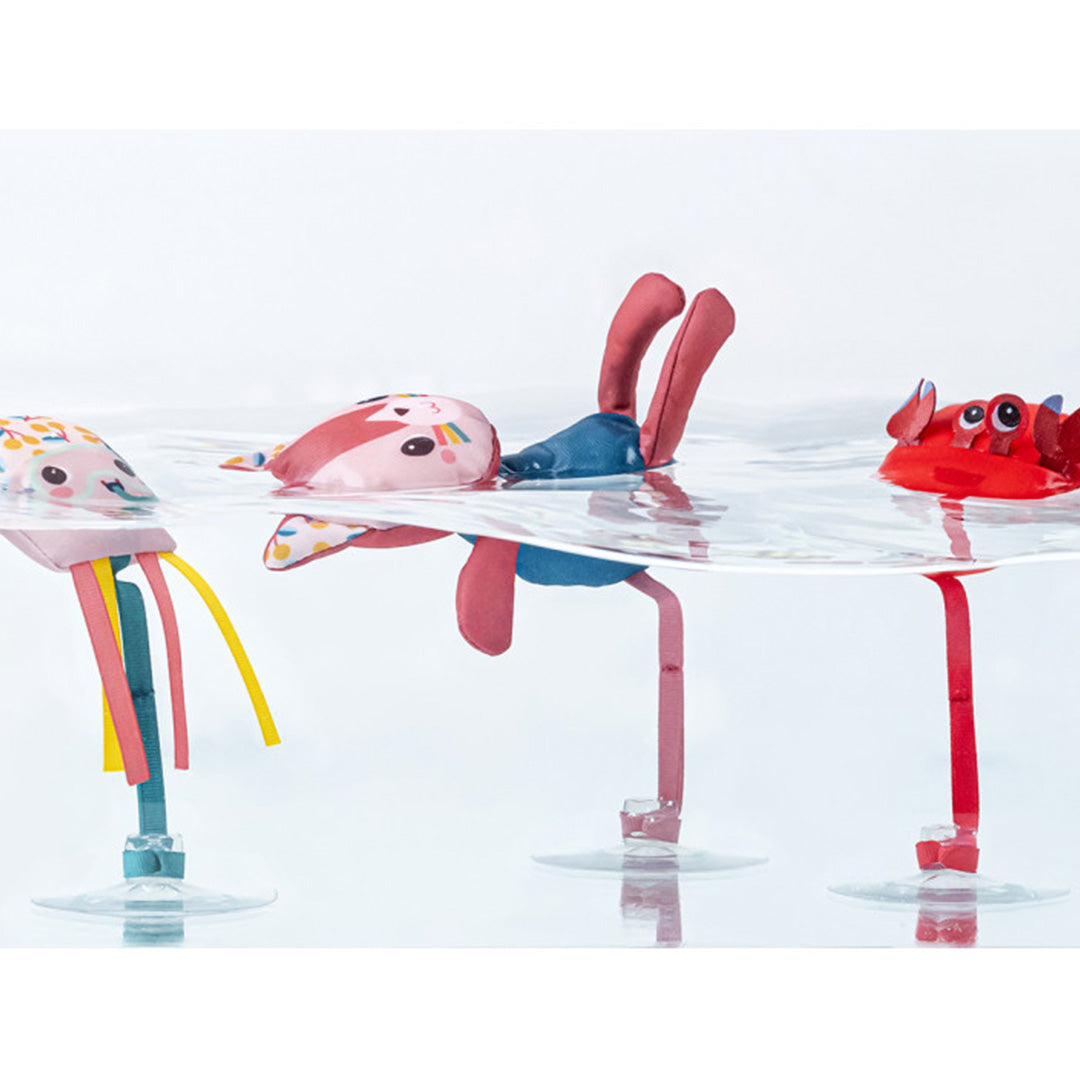 Drie Lilliputiens badfiguren, een krab, een kat en een kwal, drijven in het water.