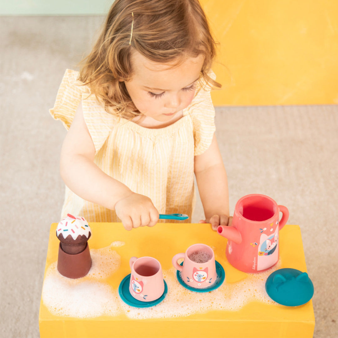 Een peuter speelt met de Lilliputiens badspeelgoed theeset, roert met een blauw lepeltje in een roze kopje met kattenfiguur.