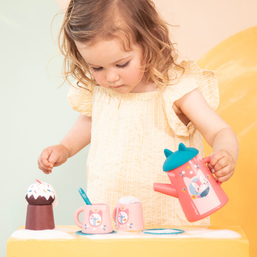 Een peuter speelt met de Lilliputiens badspeelgoed theeset, waarbij ze de roze theepot met kattenfiguur vasthoudt.