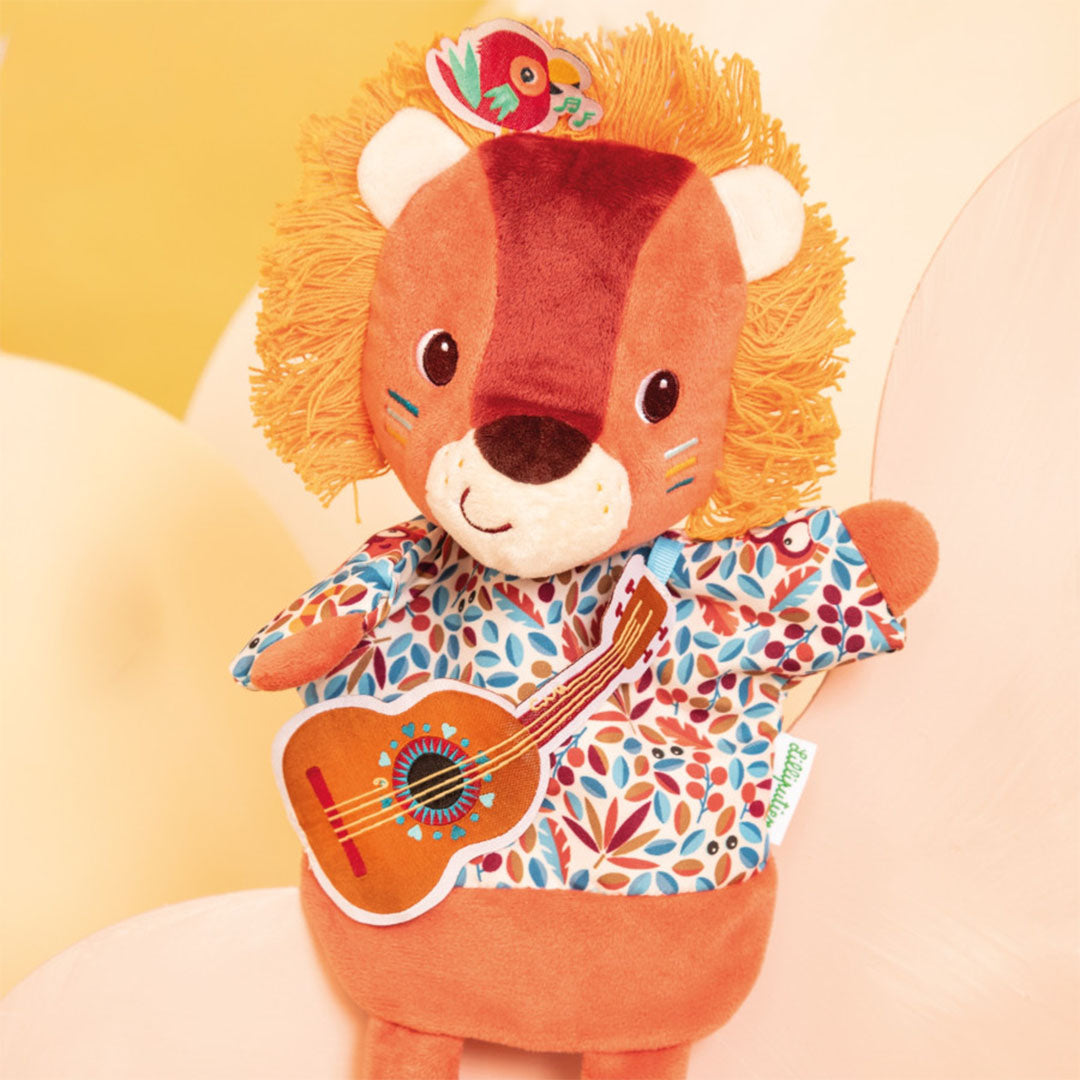 Lilliputiens handpop leeuw Jack met gitaar op een zachte gele achtergrond.