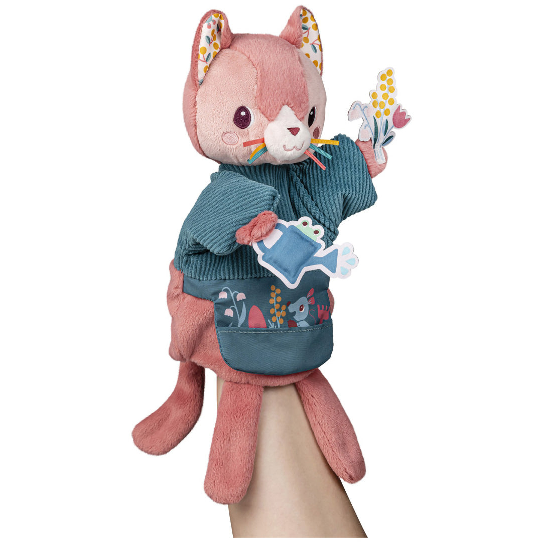 Een Lilliputiens handpop Jeanne, een roze kat met een gieter en bloemen, gedragen door een hand.