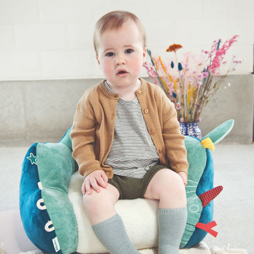Een baby zit in de Lilliputiens kinderfauteuil Joe, een zachte stoel in de vorm van een neushoorn.