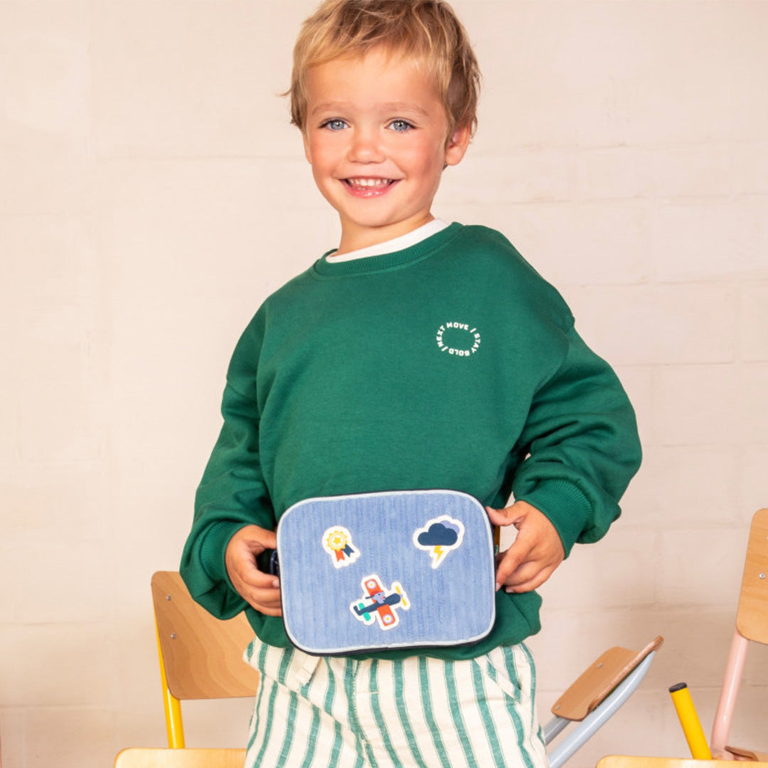 Een jongen draagt het Lilliputiens kinder heuptasje met vliegtuigpatches om zijn middel.