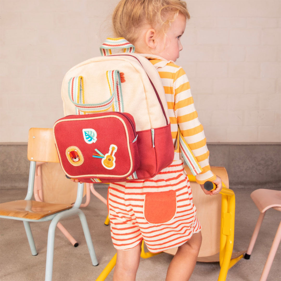 Een kind draagt de Lilliputiens kleuterrugzak met een rode lunchtas eraan bevestigd, van achteren gezien.