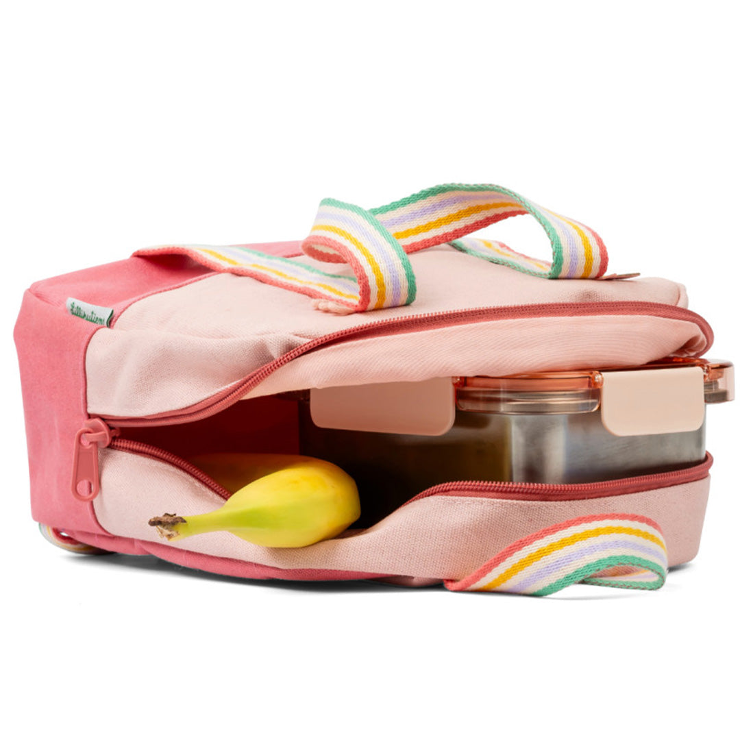 De Lilliputiens roze kleuterrugzak ligt open met een lunchbox en banaan in het hoofdvak.