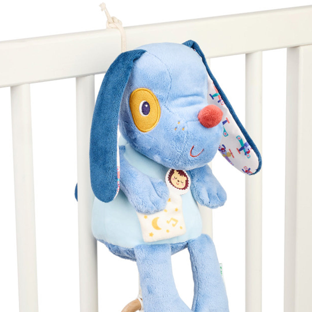 Muzieknuffel Jules de hond hangt aan de spijlen van een wit babybedje.
