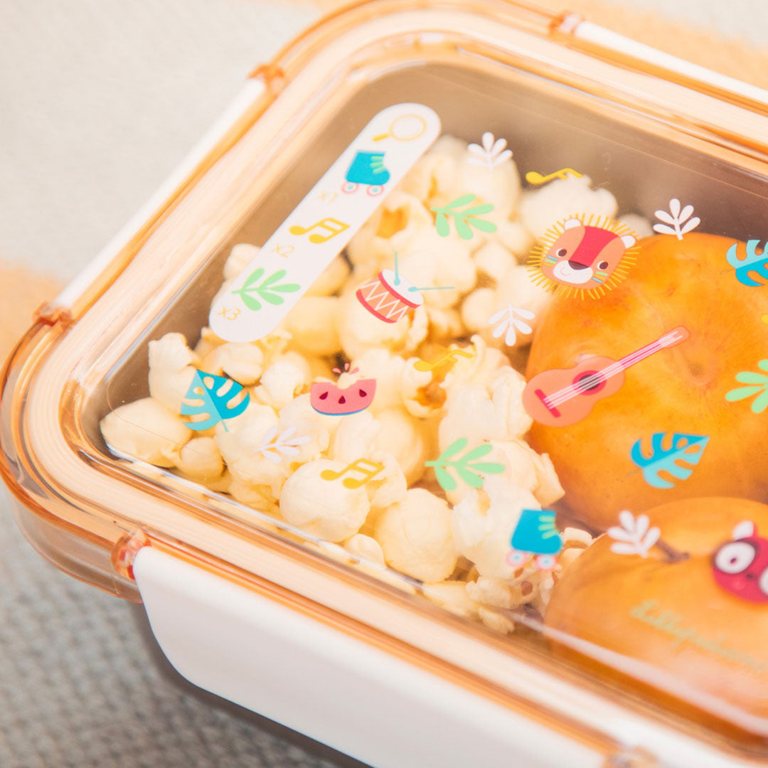 Detail van de Lilliputiens broodtrommel gevuld met popcorn en gebakjes, met deksel met dierenfiguren.