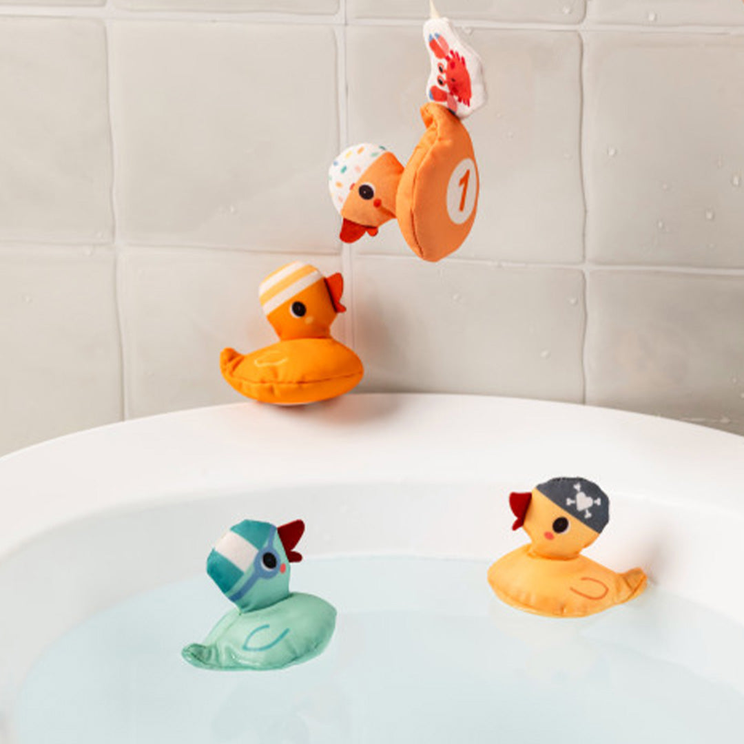 Twee Lilliputiens pluche eendjes drijven in bad, terwijl twee andere eendjes aan de vishengel hangen.
