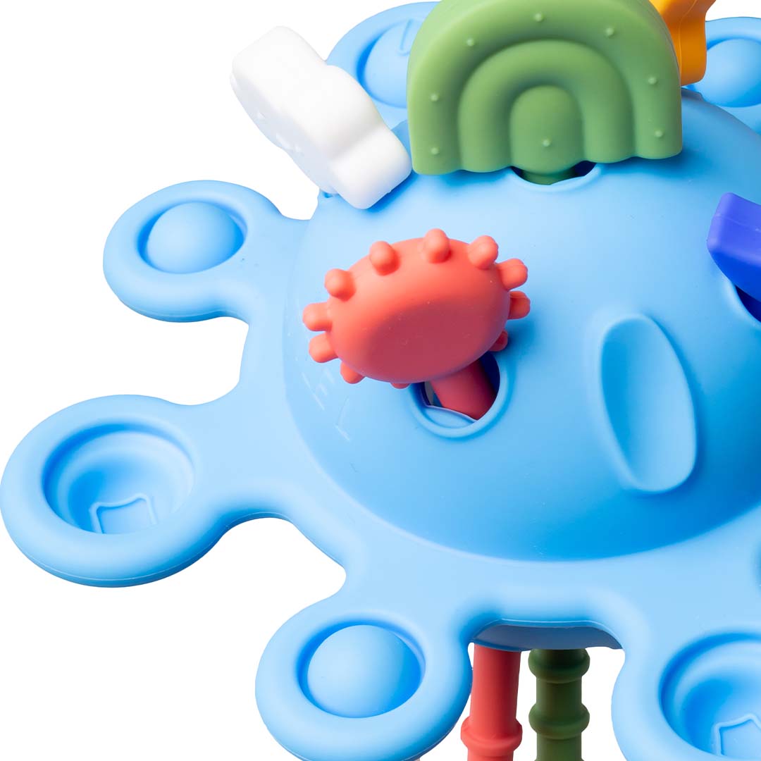 Detailopname van het little l sensorische bijtspeeltje, met een rode getextureerde trekkoord en de blauwe planeetbasis.