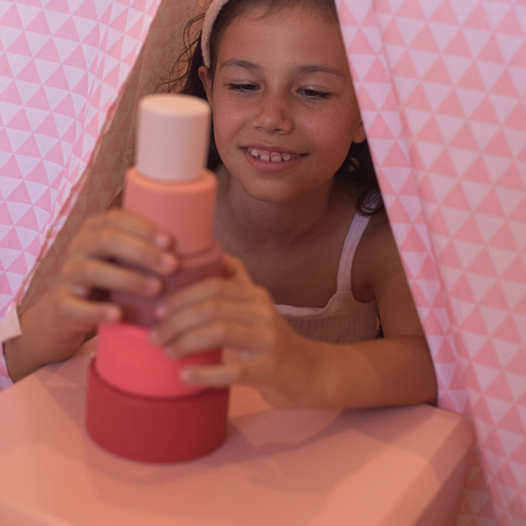 Een lachend meisje stapelt de little l rood-roze stapelkommen op elkaar.