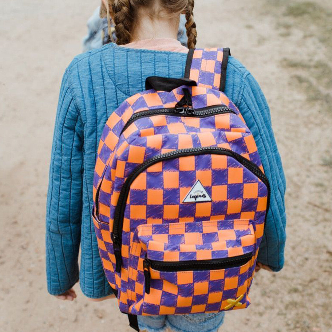 Kind draagt de Little Legends kinderrugzak met oranje en paars checkerboard patroon op de rug.