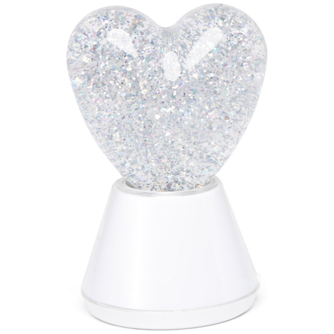 little l nachtlampje in de vorm van een hartje met zilveren glitter op een witte voet.