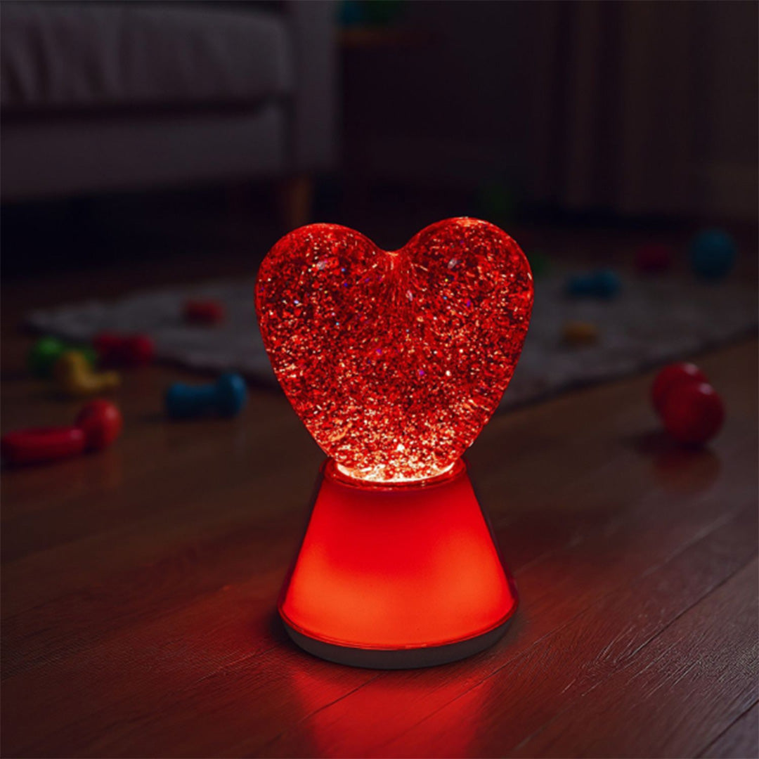 Het little l hartjes nachtlampje verlicht met rood licht op een houten vloer.