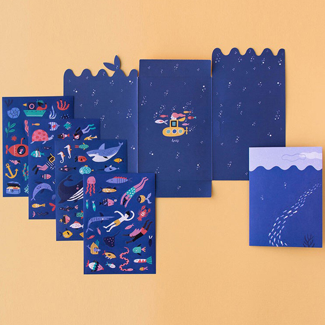 De Londji herbruikbare stickerset met meerdere vellen vol zeedieren, duikers en onderwaterobjecten, naast de gevouwen verpakking.