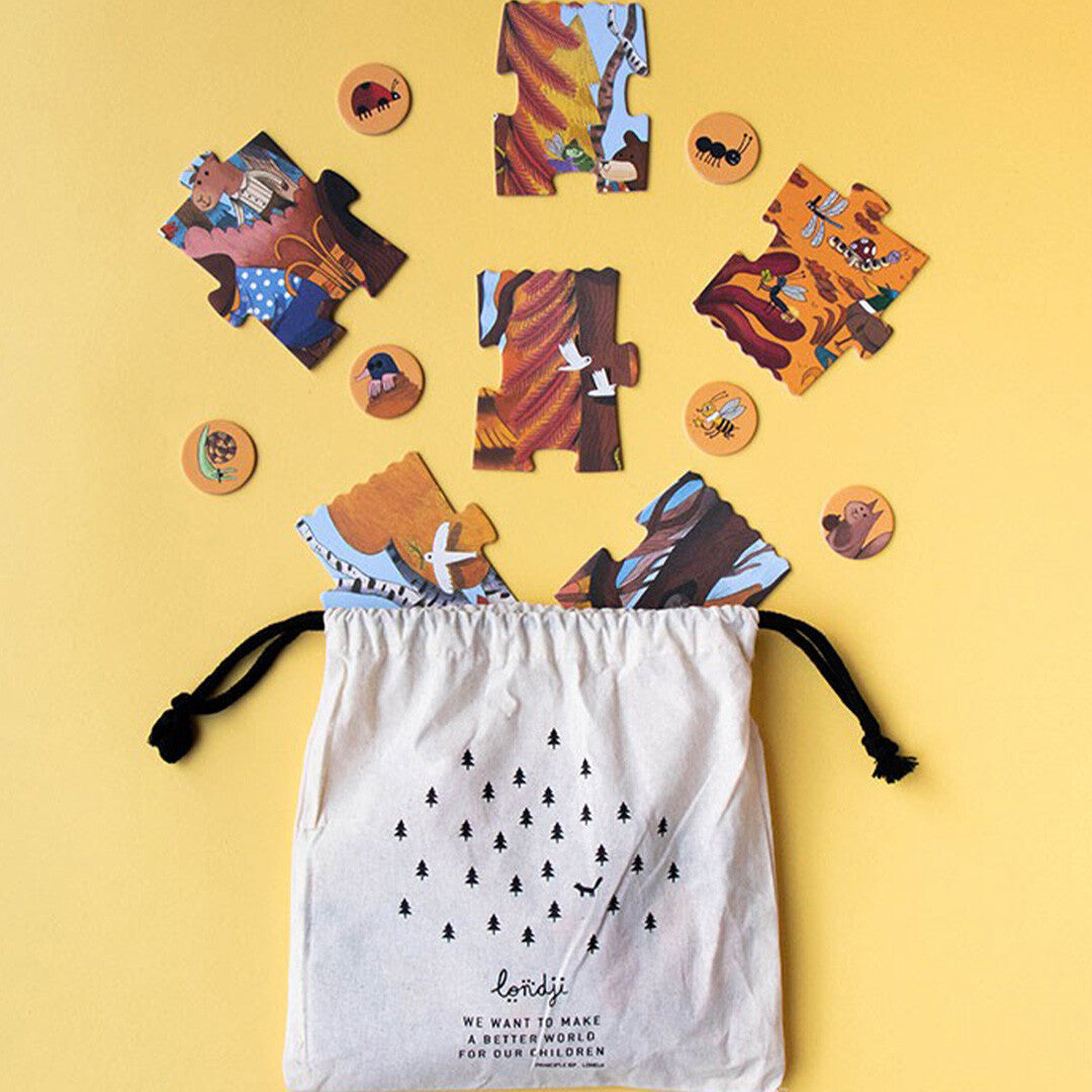 Losse puzzelstukken en zoekfiches van de Londji Bear's Forest puzzel, deels in een stoffen opbergzak.