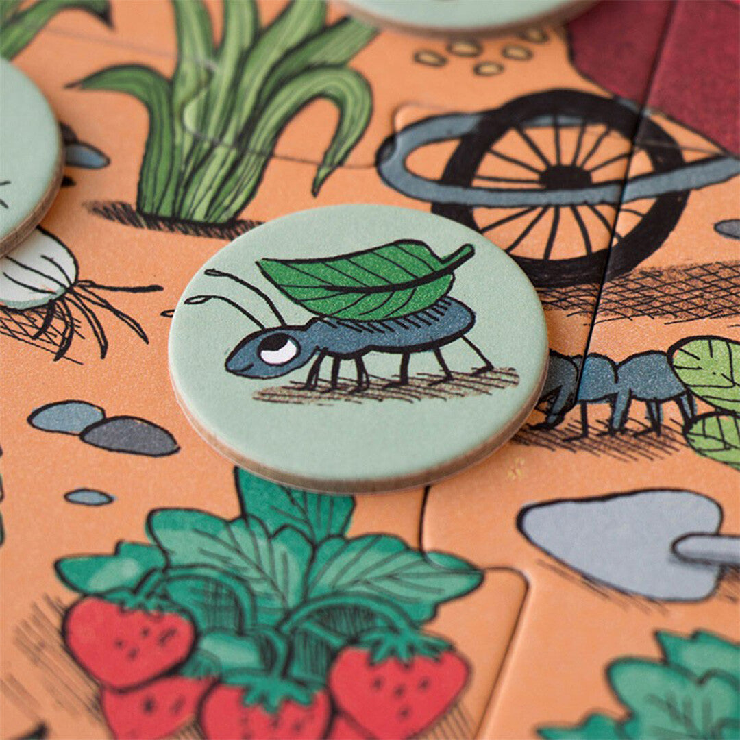 Detail van een rond zoekspel-token met een mier die een blad draagt, op de Rabbit's Garden puzzel.