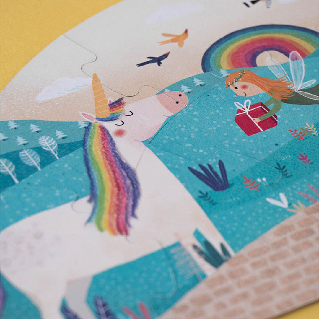 Detail van een londji legpuzzelstuk met een eenhoorn en een fee die een cadeau vasthoudt.