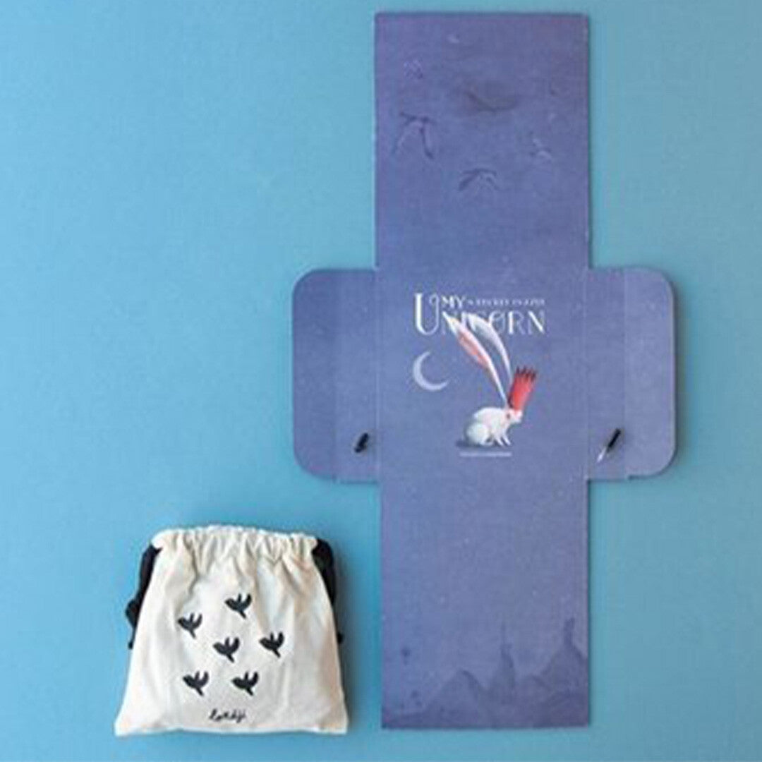 De uitgevouwen verpakking van de londji My Unicorn legpuzzel naast een wit stoffen zakje met vogels.