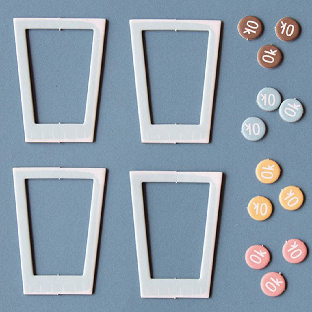 Vier lege witte milkshakebekerframes en diverse kleine ronde 'OK' fiches in verschillende kleuren.