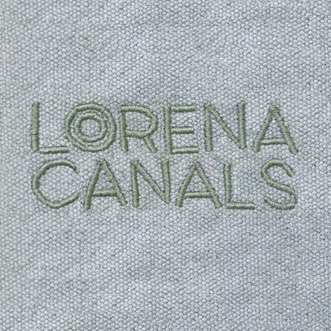 Detail van het geborduurde Lorena Canals merklogo op de blauwe canvas stof van de zitzak.