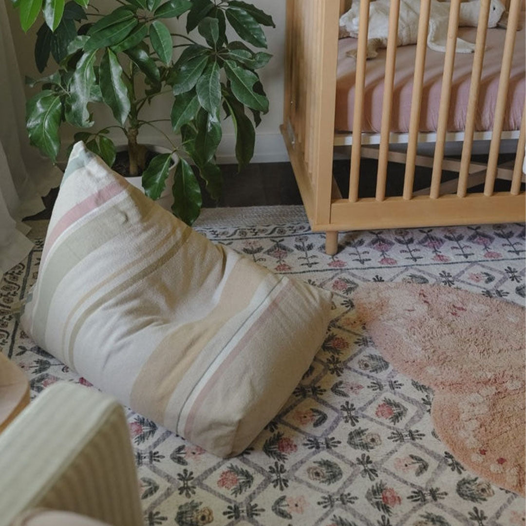 Lorena Canals poef Cleo met strepen staat in een kinderkamer naast een plant en een ledikant.