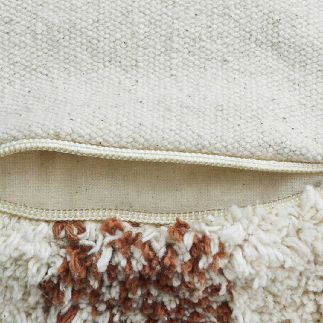 Detail van de shaggy textuur en rits van de Lorena Canals poef met toffee vichy ruitpatroon.