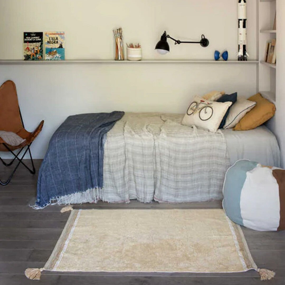 Beige gestreept vloerkleed met kwastjes op een houten vloer in een kinderkamer.