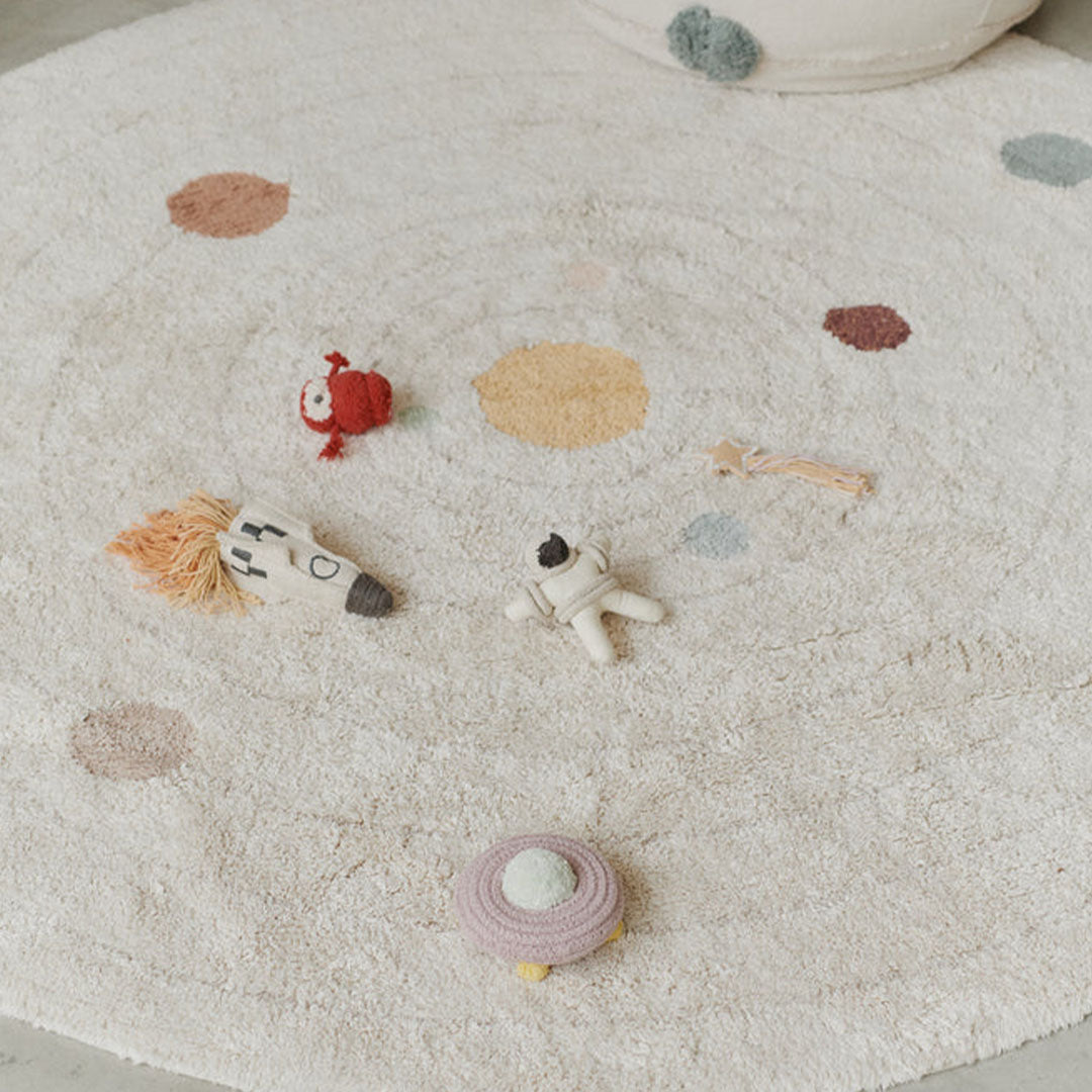 Detail van het Lorena Canals solar system vloerkleed met daarop een raket, astronaut en andere figuren.