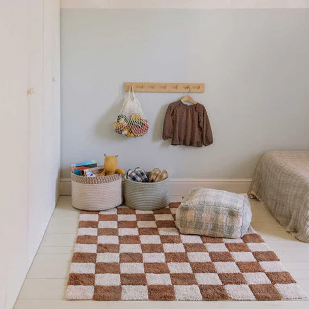 Lorena Canals vloerkleed met bruin en wit geruit patroon in een kinderkamer.