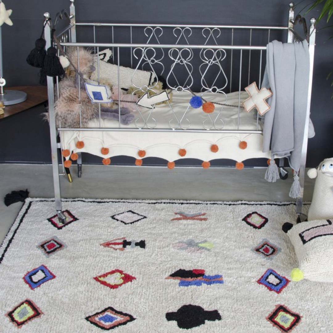 Lorena Canals wasbaar vloerkleed met etnische patronen op de vloer naast een babybedje.