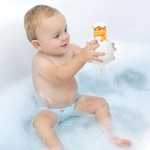 Een lachende baby in bad houdt het Ludi badspeeltje dino ei vast waar water uit spuit.