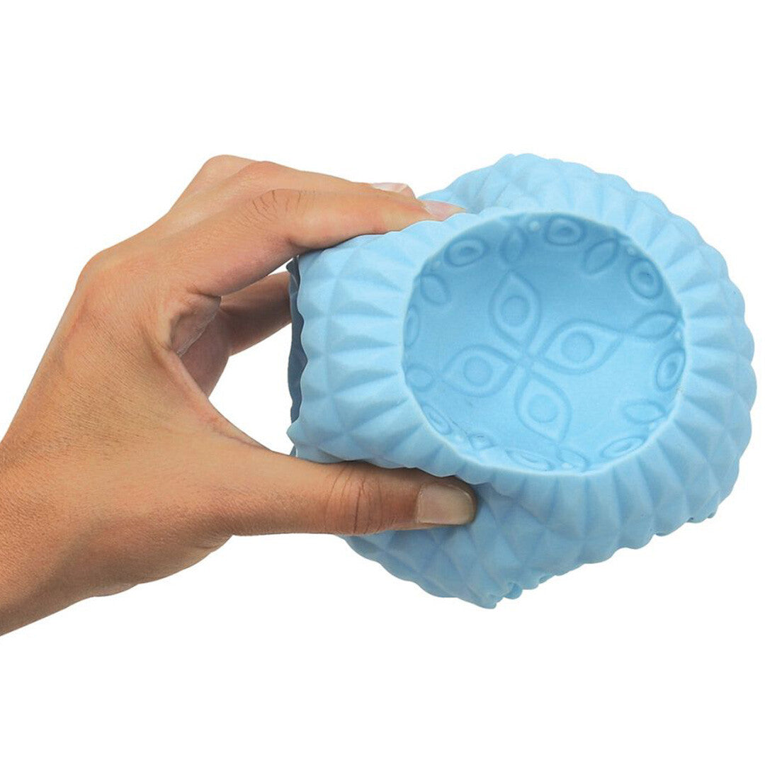Een hand houdt een blauw getextureerd onderdeel van de Ludi puzzelbal vast om de grootte te tonen.