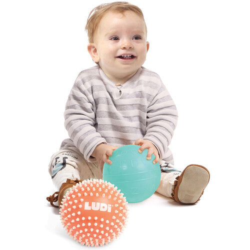 Een lachende baby speelt met de Ludi sensorische ballen.
