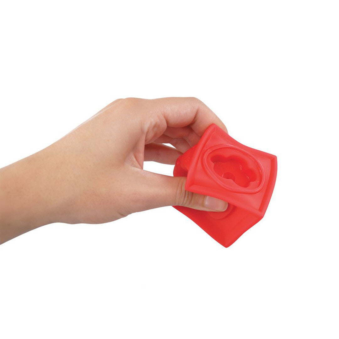 Een hand knijpt in een rood Ludi sensorisch blok om de zachte textuur te tonen.
