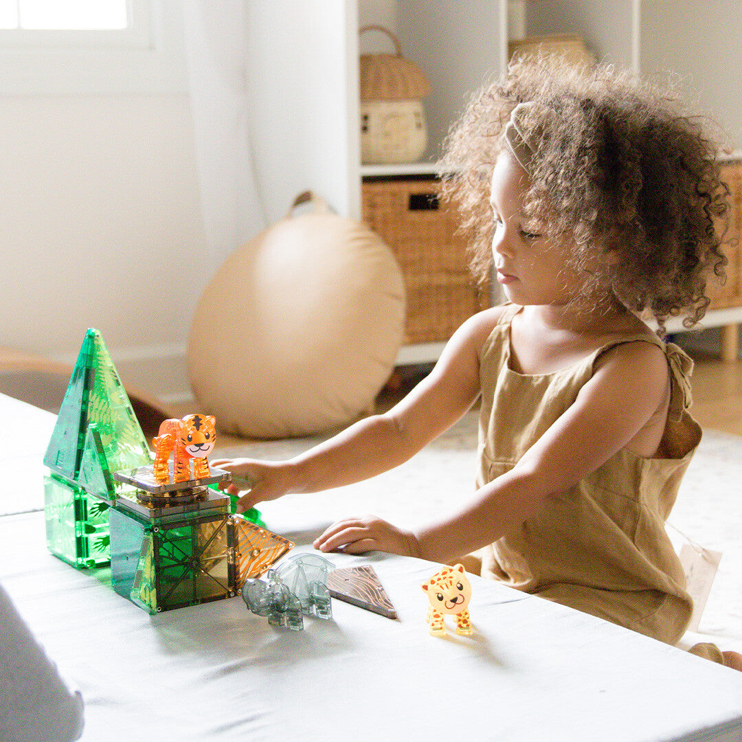 Een jong kind speelt met de Magna-Tiles Jungle Animals bouwset op een tafel.