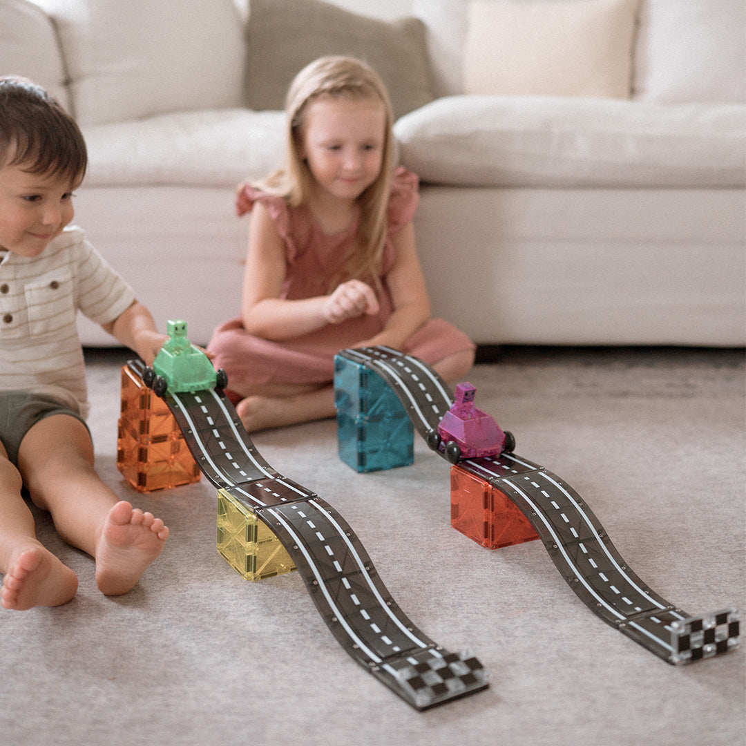 Twee kinderen spelen op de vloer met de Magna-Tiles magnetische autobaan downhill duo set.