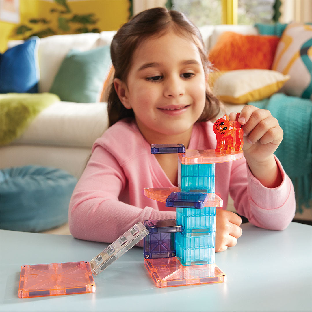Een lachend meisje speelt met de Magna-Tiles Cat Tree bouwset en houdt het kattenfiguur bovenop de kattenboom.