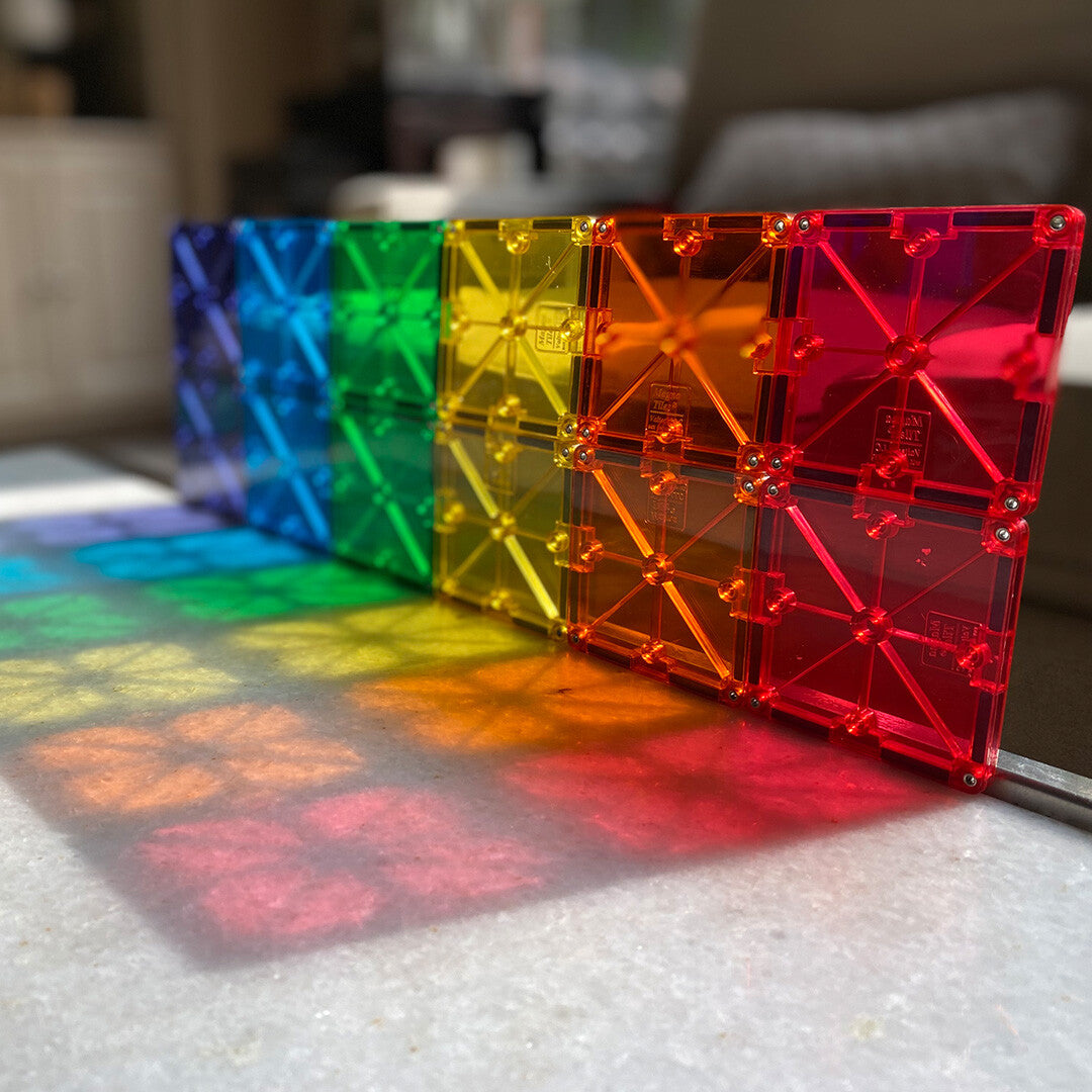 Close-up van kleurrijke Magna-Tiles magnetische tegels die regenboogschaduwen werpen.