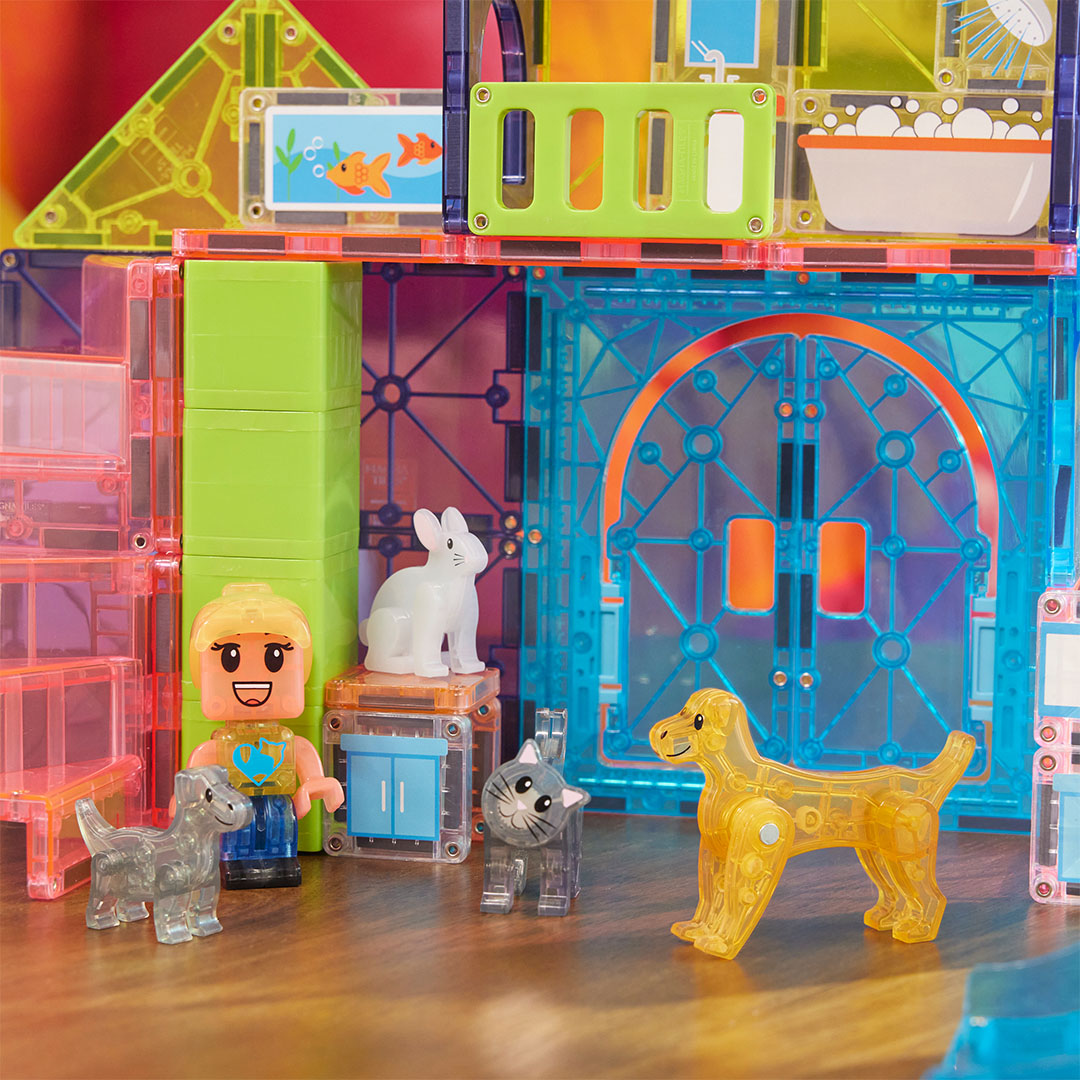 Detail van de Magna-Tiles Pet Playhouse bouwset met een kindfiguur, konijn, kat en hond voor de ingang van het huis.