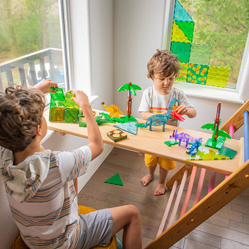 Twee kinderen spelen met de Magna-Tiles Dino World XL bouwset, bouwend met magnetische tegels en dinosaurusfiguren.