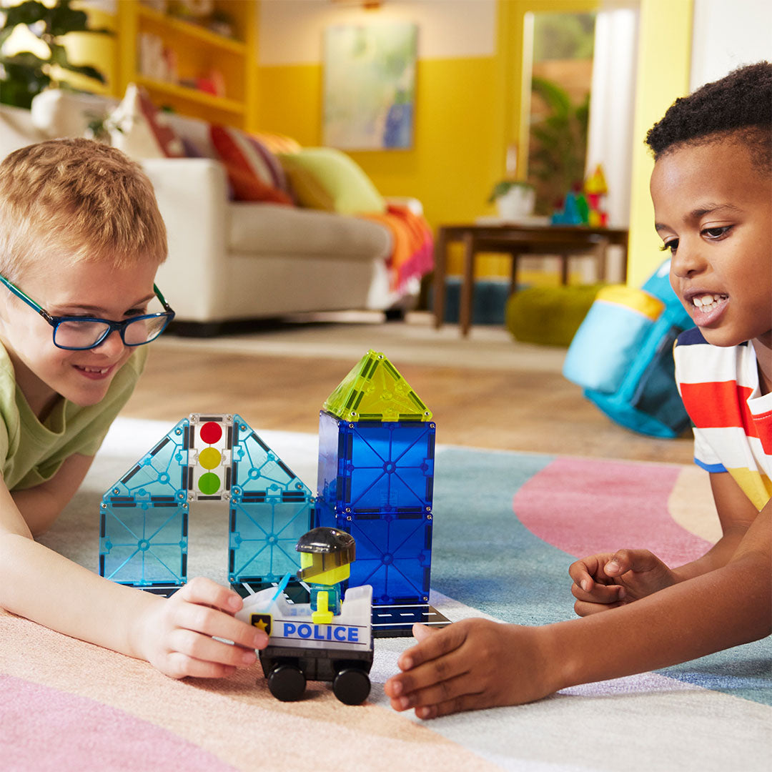 Twee kinderen spelen samen op de grond met de Magna-Tiles Police Patrol bouwset.